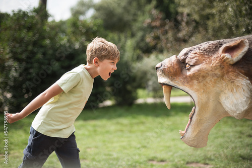 Boy shouts in front of the saber-toothed tiger figure photo