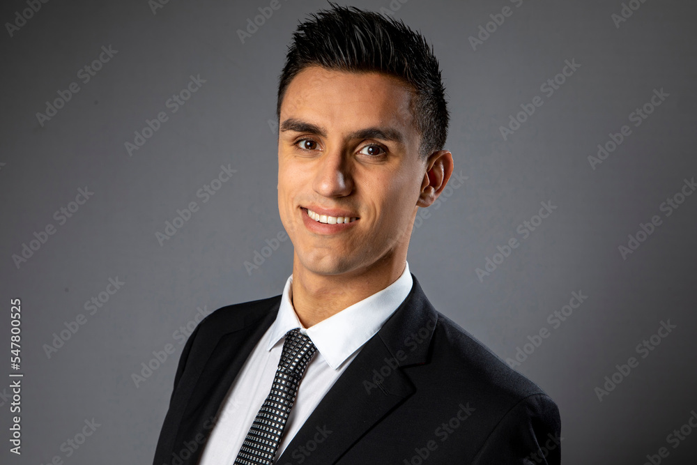 Man in a suit and tie smiling at the camera on a gray background Man in a suit and tie smiling at the camera on a gray background