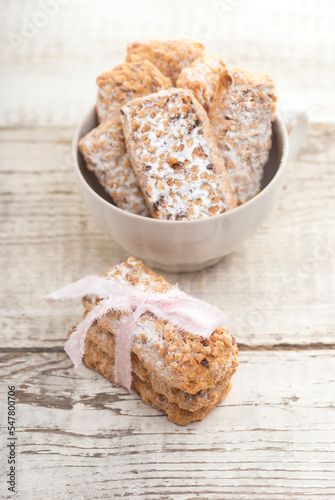 Homemade cookies with nuts and powdered sugar in a cup on a white wooden table.