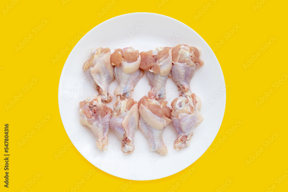 Fresh raw chicken wings (wingstick) in white plate on yellow background. Fresh raw chicken wings (wingstick) in white plate on yellow background.