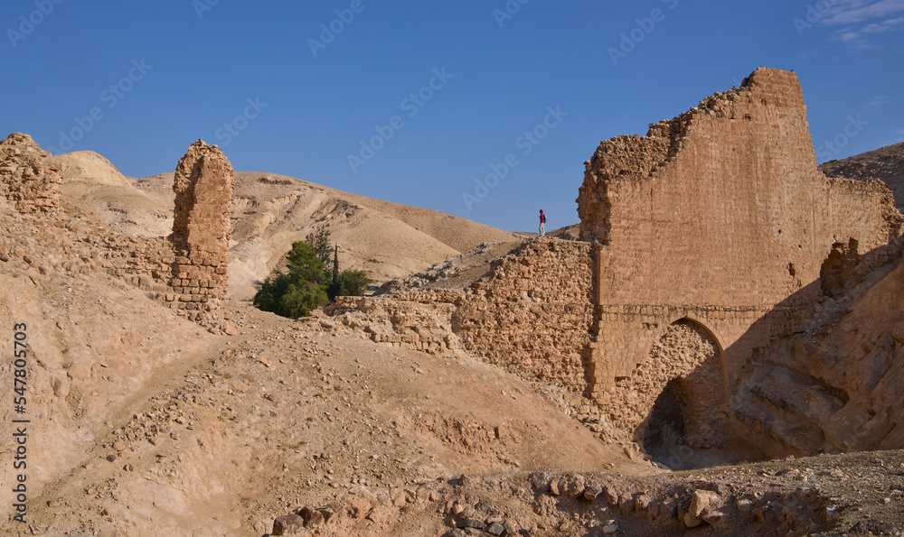 Fototapeta premium Female posing on the remains of aqueduct from the Roman period carrying water to the wadi Qelt valley in Judean Desert near Jericho city. Remains of a beautiful overpass resting on a number of arches.