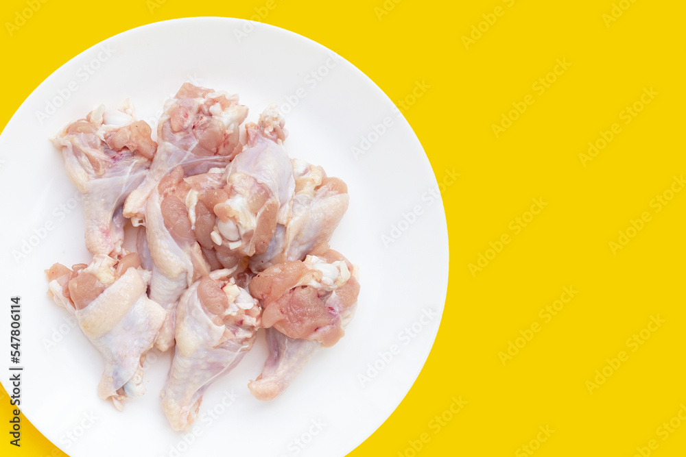 Fresh raw chicken wings (wingstick) in white plate on yellow background. Fresh raw chicken wings (wingstick) in white plate on yellow background.