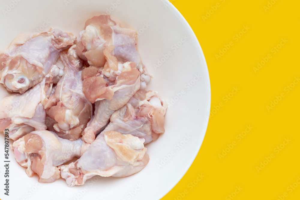 Fresh raw chicken wings (wingstick) in white plate on yellow background.