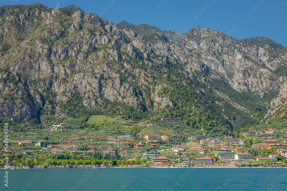 Idyllic Lake Garda and Limone sul Garda old town with boat, Italian alps