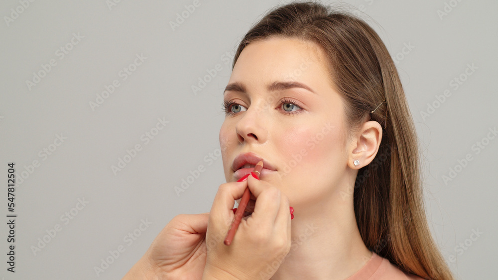 Makeup artist or stylist applies lipstick to the lips of the female model. Visagiste making make up applying lipstick on a lip. Professional makeup. Makeup artist or stylist applies lipstick to the lips of the female model. Visagiste making make up applying lipstick on a lip. Professional makeup.