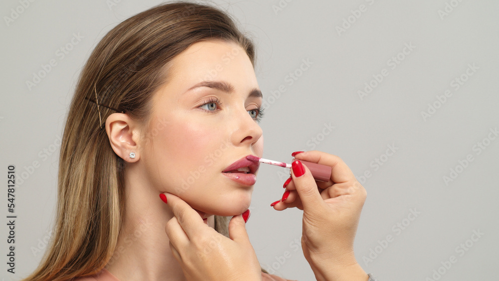 Makeup artist or stylist applies lipstick to the lips of the female model. Visagiste making make up applying lipstick on a lip. Makeup artist or stylist applies lipstick to the lips of the female model. Visagiste making make up applying lipstick on a lip.