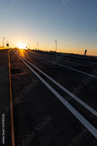 Vertical shot of road on a bridge leading towards sunrise