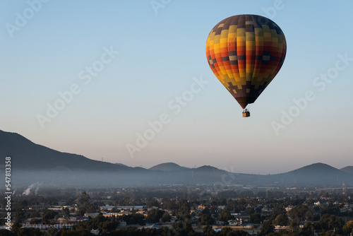 A Hot Air Balloon rises above the countryside as the sun rises © Richard
