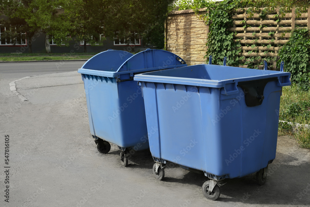 Two open blue dumpsters with wheels on city street Two open blue dumpsters with wheels on city street