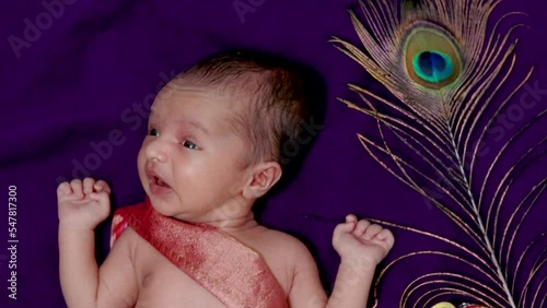 newborn baby boy in krishna dressed sneezing expression from top angle photo