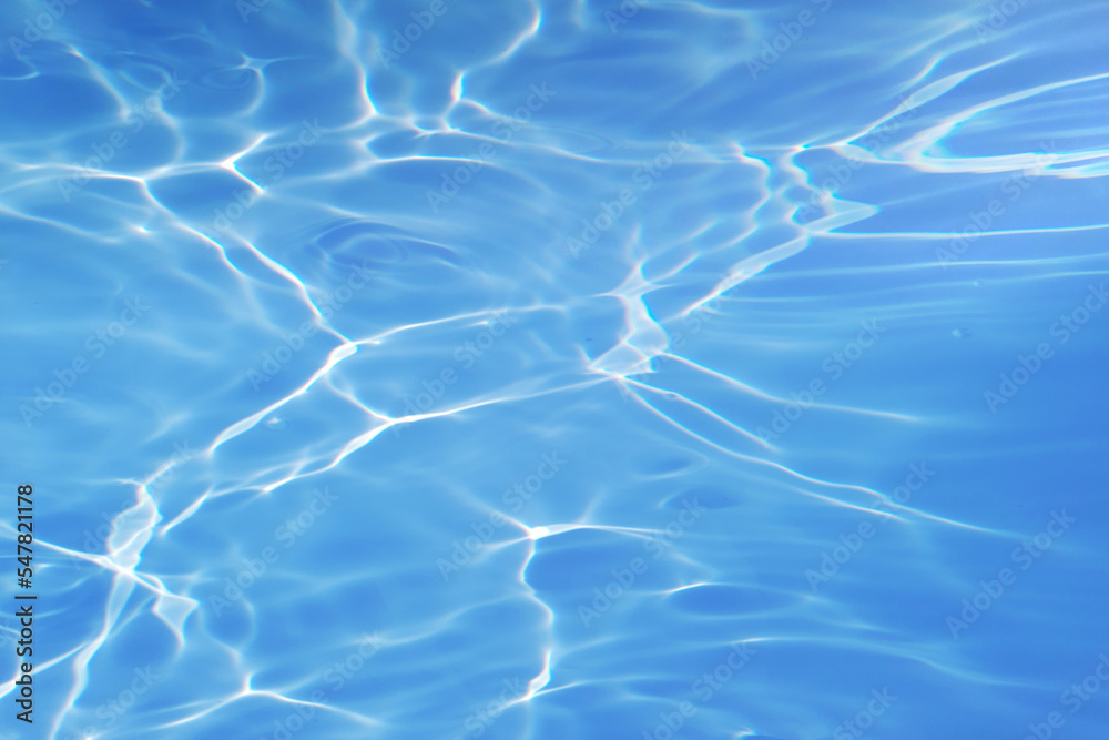 Bluewater waves on the surface ripples blurred. Defocus blurred transparent blue colored clear calm water surface texture with splash and bubbles. Water waves with shining pattern texture background. Bluewater waves on the surface ripples blurred. Defocus blurred transparent blue colored clear calm water surface texture with splash and bubbles. Water waves with shining pattern texture background.