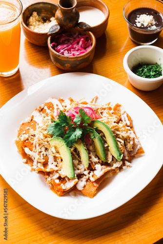 Traditional Mexican dish, chilaquiles with avocado, chicken and cream.