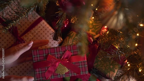 Close-up view of hands putting Christmas gift under the xmas tree