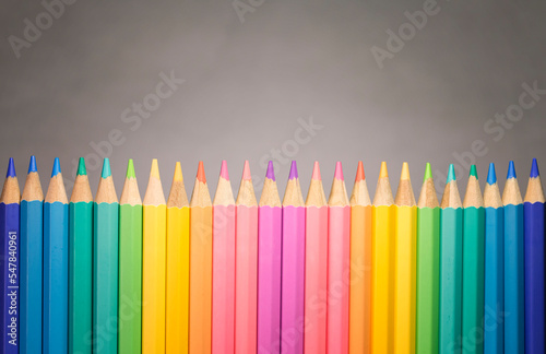Collection of color pencild laying in row striaght line made by pencil tips with grey background close up, Color pancils, copy space, Pastel color, Office and school equipment, Education concept photo