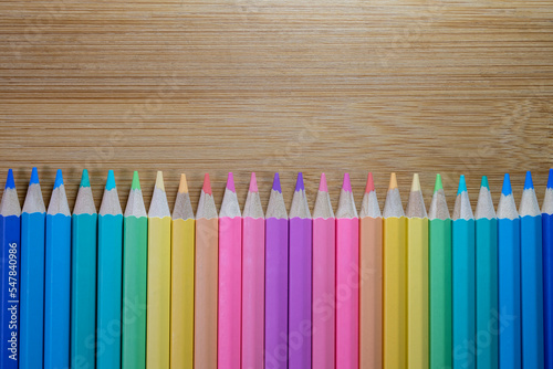 Group of color pencild laying in row striaght line made by pencil tips on wooden table background close up, Color pancils, copy space, Pastel color, Background, Education concept. photo