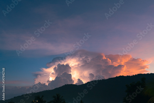 Lightning flashes through the colorful cloud over mountain in the sunset sky