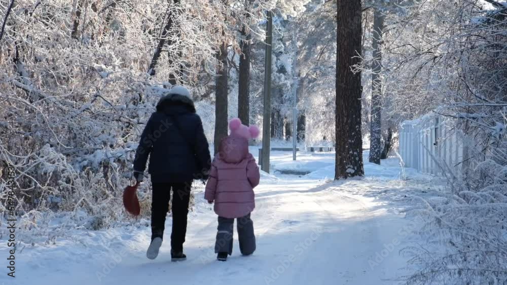 Grandmother with granddaughter walking in snow on nice winter day. Happy winter day	