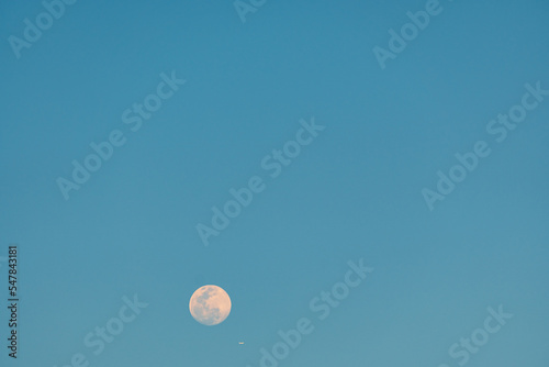 Full moon and airplane in the blue sky