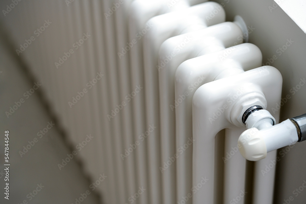 A man's hand holds a heating thermostat knob. The concept of the cost of heating services, the increase in prices for utilities A man's hand holds a heating thermostat knob. The concept of the cost of heating services, the increase in prices for utilities