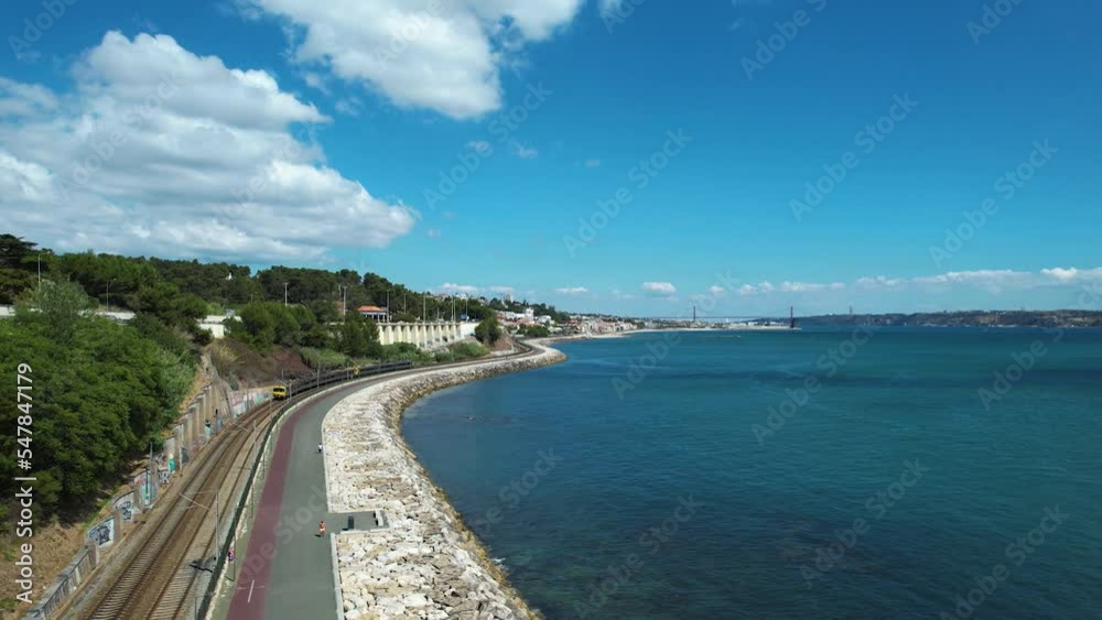 Aerial view following a train on the coastline of sunny Caxias, Lisbon, Portugal Aerial view following a train on the coastline of sunny Caxias, Lisbon, Portugal