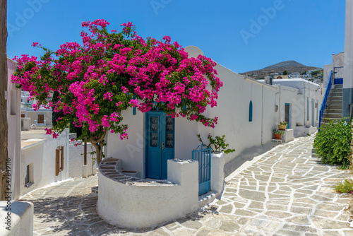 Traditional Cycladitic alley with a narrow street, whitewashed houses and a blooming bougainvillea in lefkes village, Paros island, Greece. photo