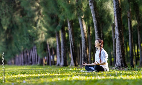 Panorama of woman relaxingly practicing meditation in the pine forest to attain happiness from inner peace wisdom for healthy mind and soul concept