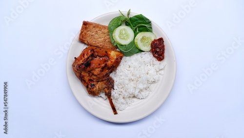 Ayam Bakar Kecap. soy sauce grilled chicken served with rice, Tempe bacem, fresh vegetables and sambal. photo