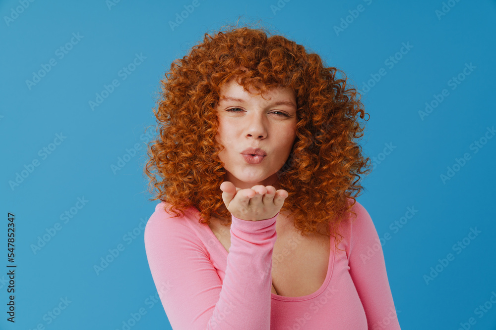 White ginger woman with curly hair blowing air kiss at camera Stock