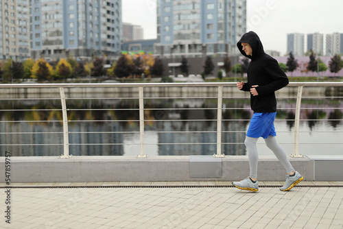 Middle age european man wearing in warm sportswear running at riverside. Morning run concept.