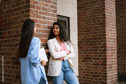Young indian women smiling and talking while standing by building