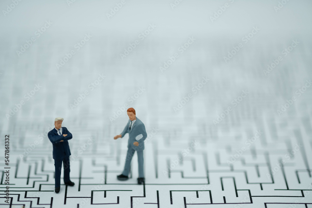 Miniature Business man thinking how to solve this problem.Business obstacle,financial,business growth concept.Business man stand on center of maze. Miniature Business man thinking how to solve this problem.Business obstacle,financial,business growth concept.Business man stand on center of maze.