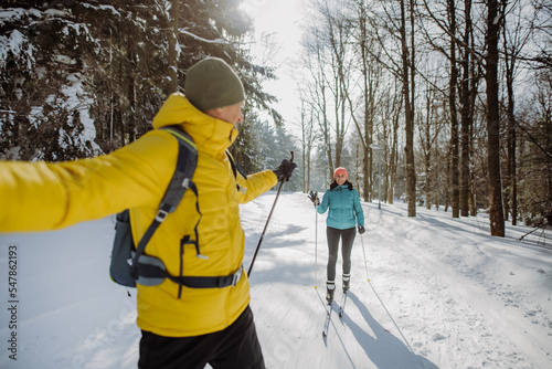 Senior couple skiing together in the middle of forest.
