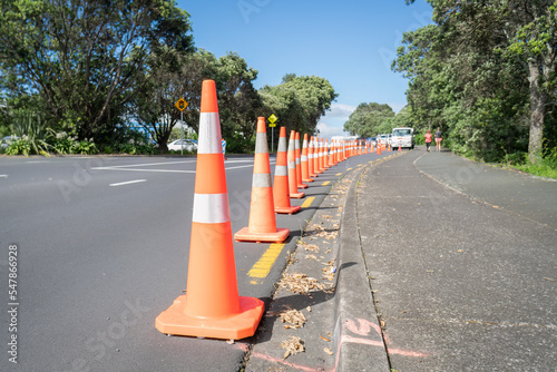 Obraz na płótnie Orange traffic cones along the road, blurred people walking on the footpath. Auckland. w salonie