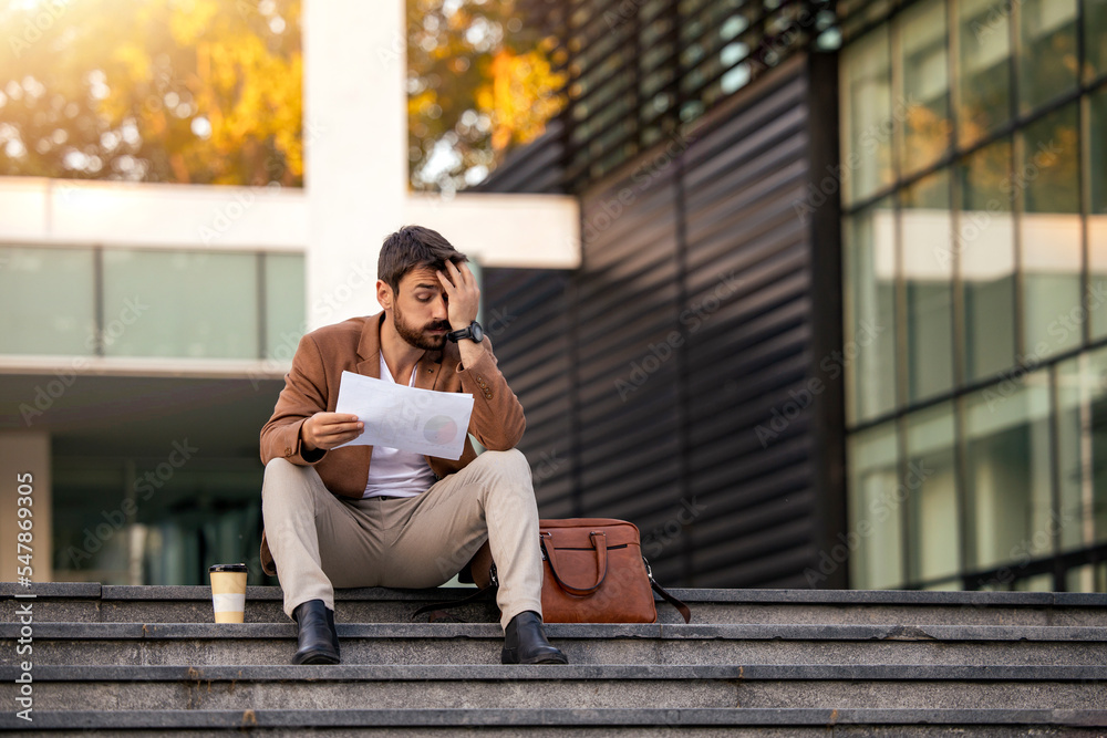 Businessman sitting on the stairs and read some documents Businessman sitting on the stairs and read some documents