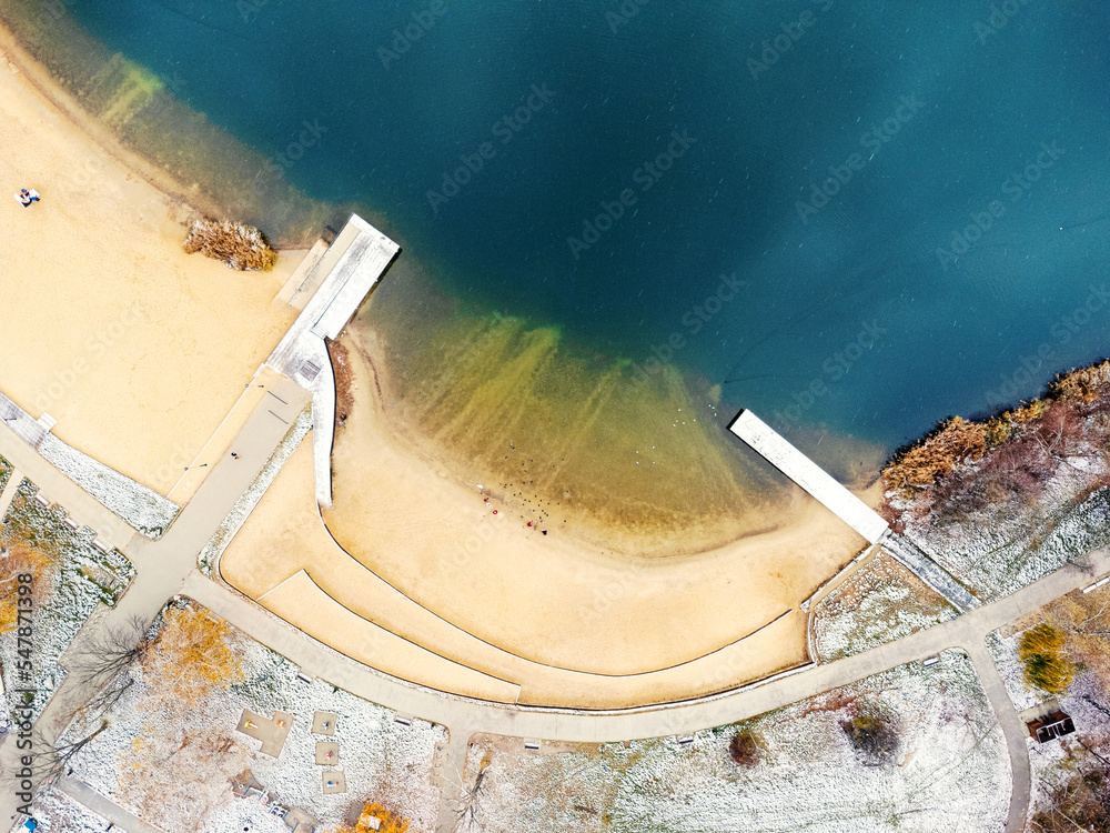 Aerial view of beautiful wooden pier, sea bay, sandy beach at winter. Aerial view of pier, transparent blue water. Frost and some snow. Pond, lake, Poland Bagry.