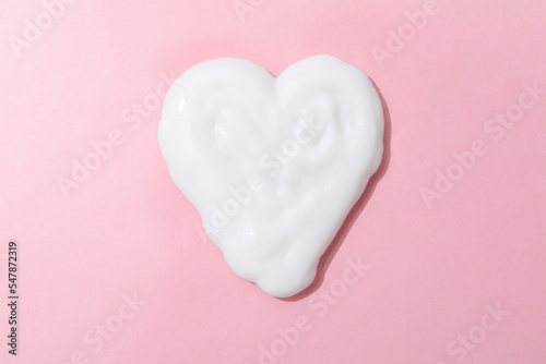Heart made of cream on pink background