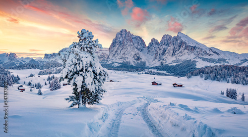 Happy New Year celebration concept. Snowy winter view of Alpe di Siusi village with Plattkofel peak on background. Amazing morning scene of Dolomite Alps with country road, Ityaly, Europe.