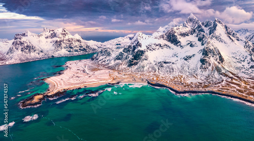 Majestic spring sunset on Lofoten Islands. Aerial view from flying drone of Snowy mountain range. Splendid evening seascape of Norwegian sea. Beauty of nature concept background.