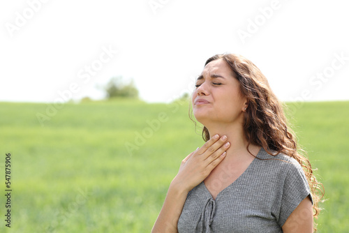 Stressed woman suffering throat ache in a field