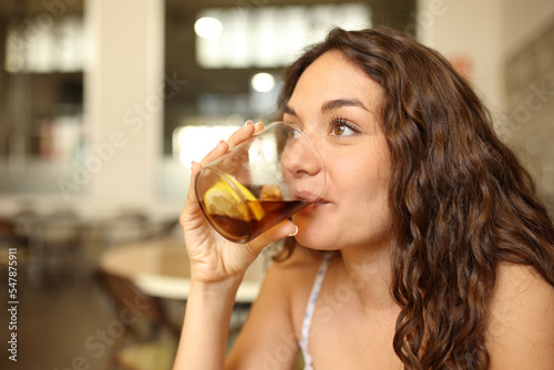 Woman drinking soda looking away in a bar