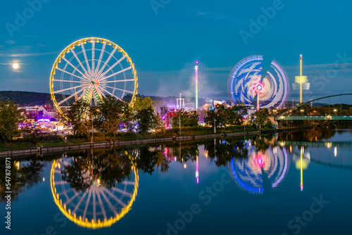 Germany, Baden-Wurttemberg, Stuttgart, Amusement park rides glowing in riverside festival area at night photo
