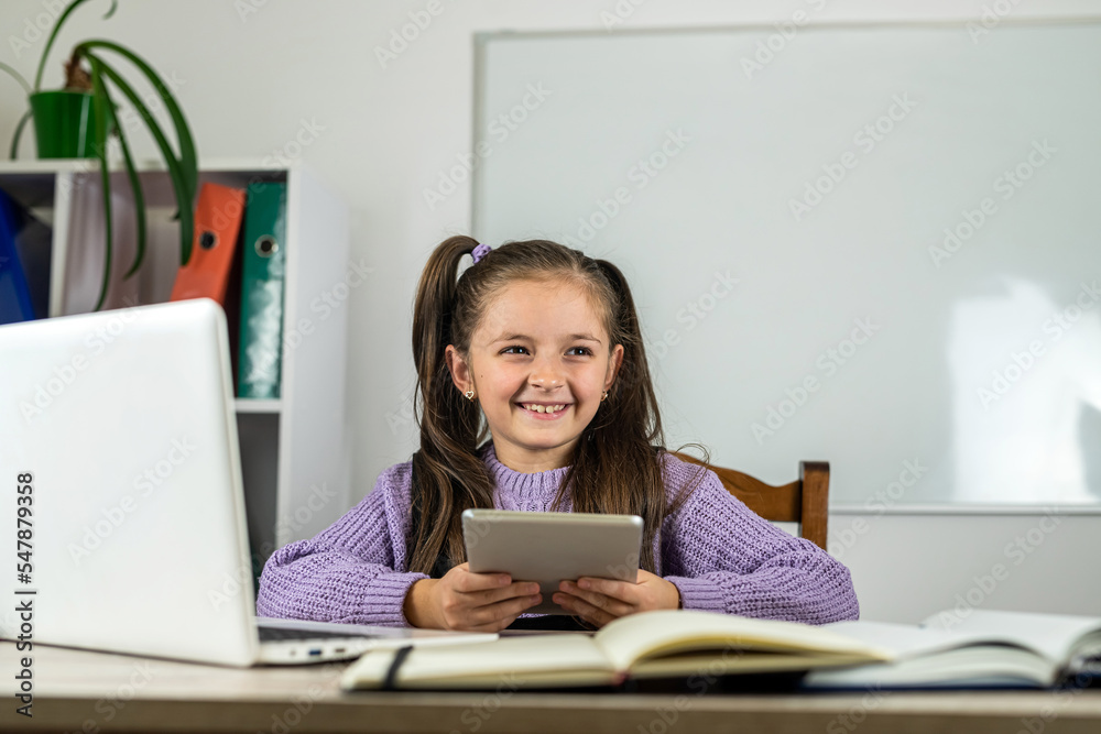 smiling little girl is watching a video lesson on the computer. smiling little girl is watching a video lesson on the computer.