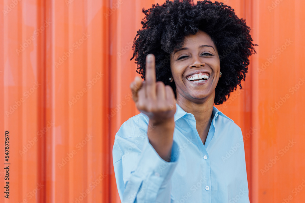 Happy woman in afro hairstyle showing middle finger Happy woman in afro hairstyle showing middle finger