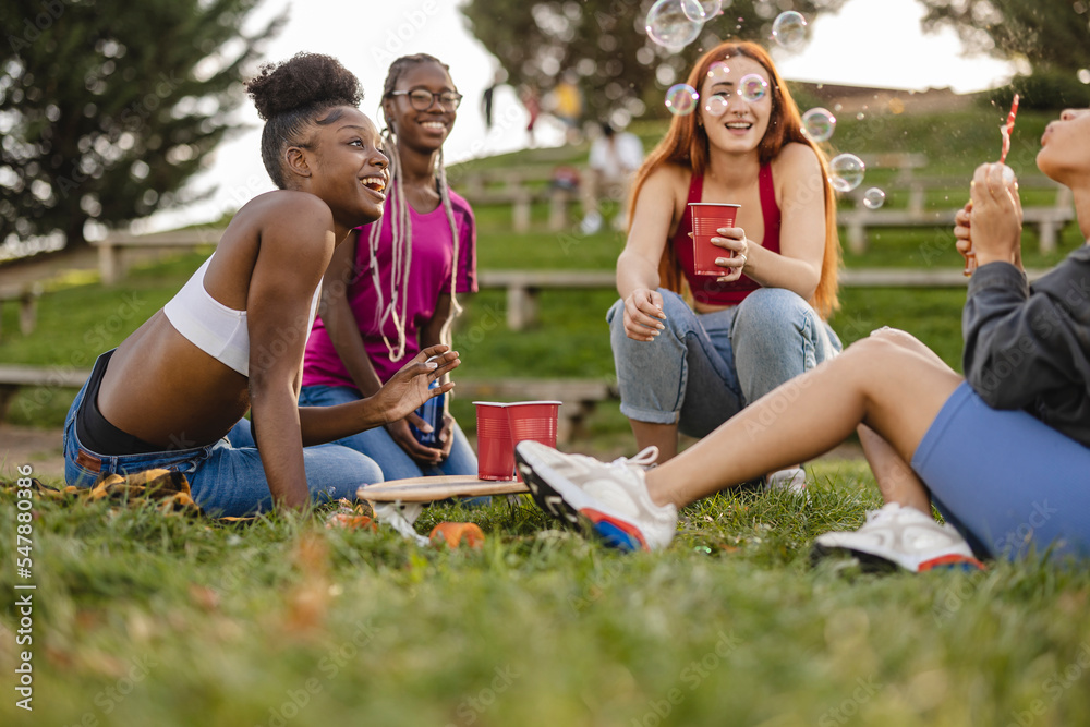 Happy woman blowing bubbles with friends enjoying at park Happy woman blowing bubbles with friends enjoying at park