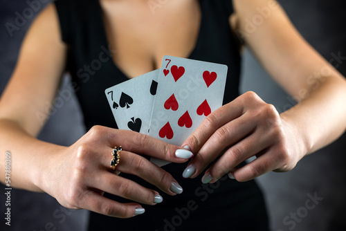 Beautiful girl in black dress holds ace of poker cards near sexy cleavage.