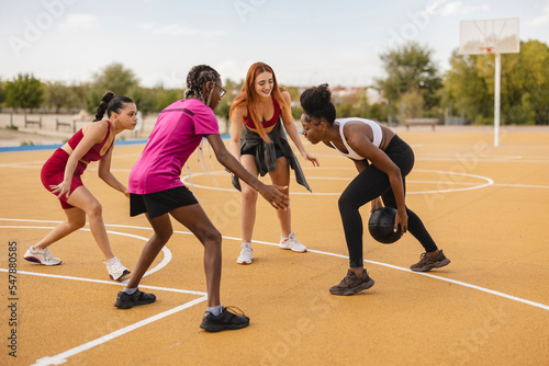 Young woman with friends playing basketball at sports court photo
