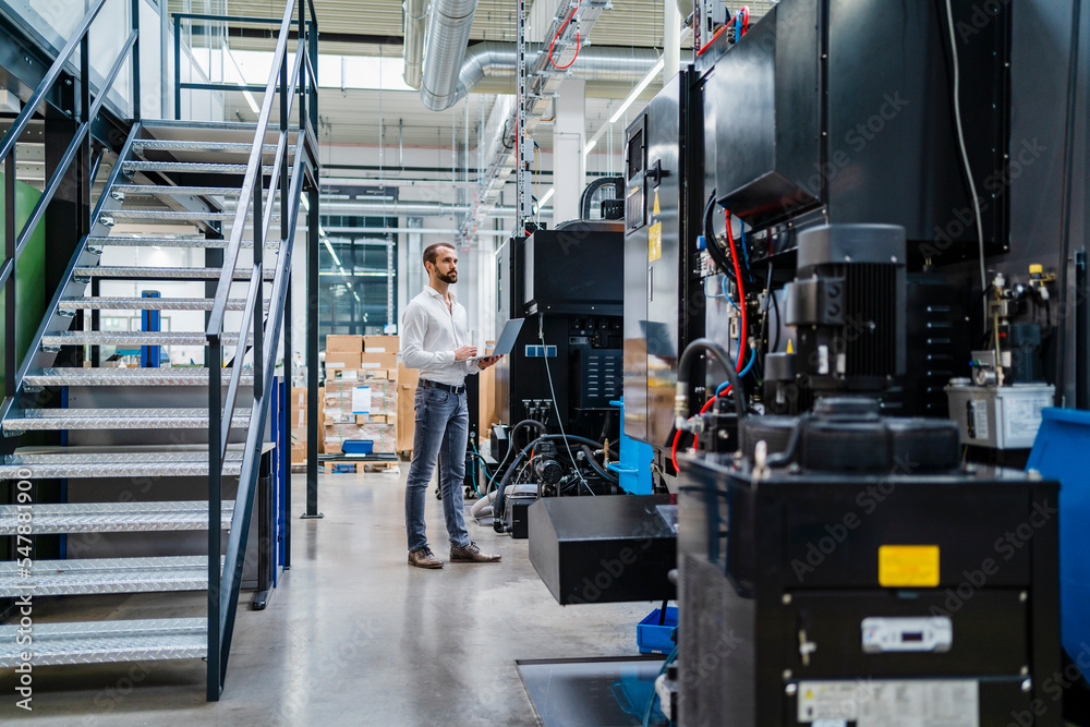 Young businessman examining machines in factory Young businessman examining machines in factory