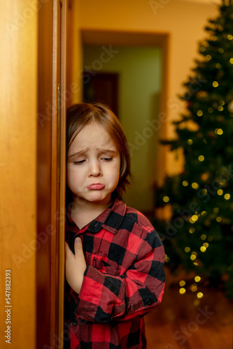 Sad boy standing near doorway at home