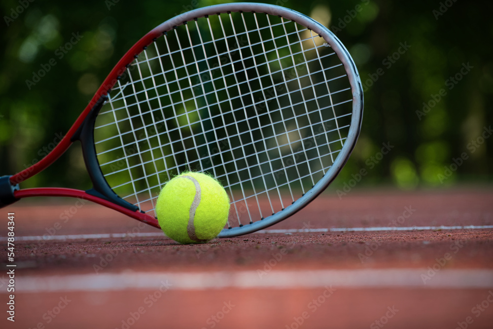 Yellow tennis ball near racquet and white line