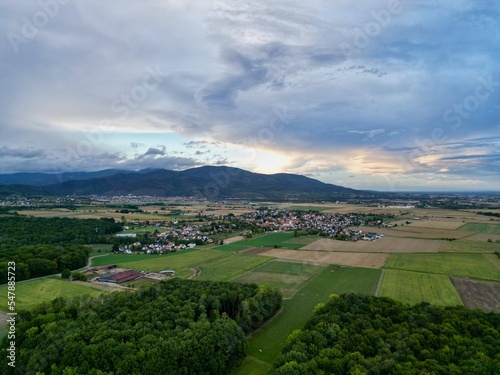 Wallpaper Mural Panoramic aerial drone top view of the village of Aspach-Michelbach (Upper-Rhine, Alsace, France) at sunset by cloudy weather in summer, with Vosges mountains in background Torontodigital.ca